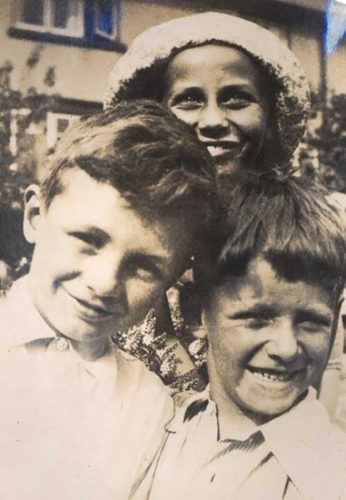 Deux garçons et une fille derrière eux sourient à la caméra.