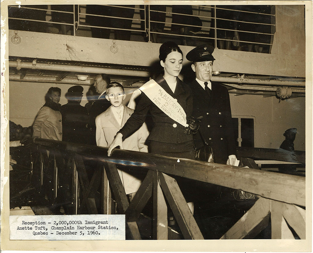 Une jeune femme descend une passerelle, escortée par un fonctionnaire du port.