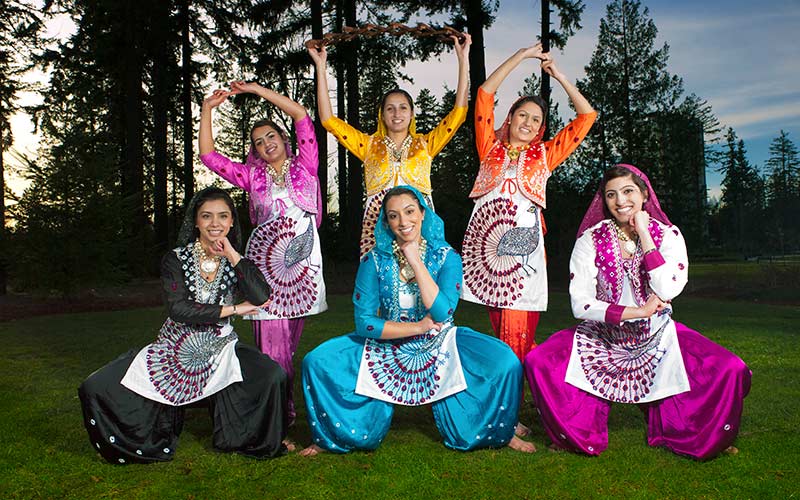 Six danseuses de Bhangra posent en tenue culturelle.