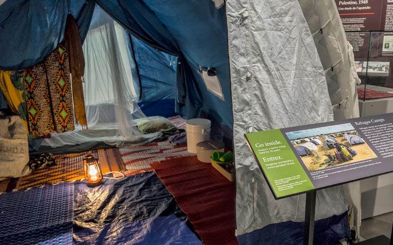 Une tente utilisée dans les camps de réfugiés, avec un panneau d’exposition qui dit « Entrez »