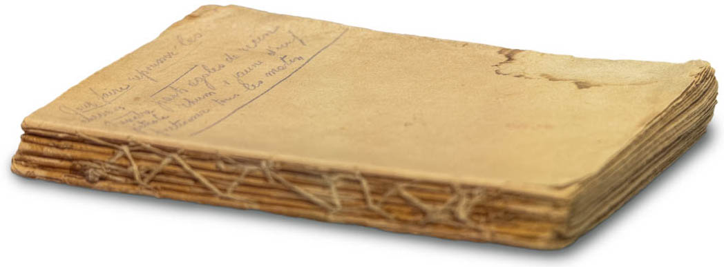 Un livre sans couverture, avec des pages cousues ensemble à la reliure. Il y a de l’écriture manuscrite et une tache sur la première page jaunie.