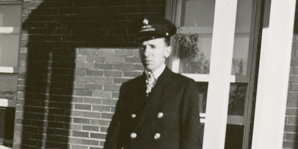 Un homme en casquette et en uniforme regarde vers la caméra.