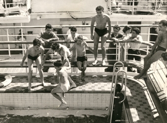 Plusieurs jeunes garçons sautant dans la piscine du navire.