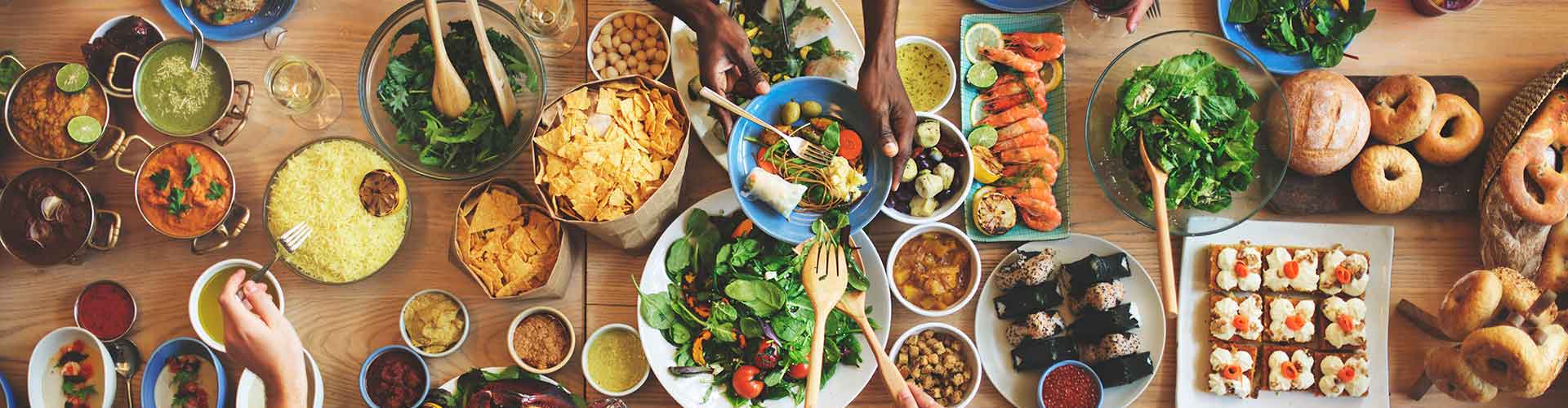  Du curry, du riz, des fruits de mer, des salades et des pains de différentes cultures sont disposés sur une grande table.