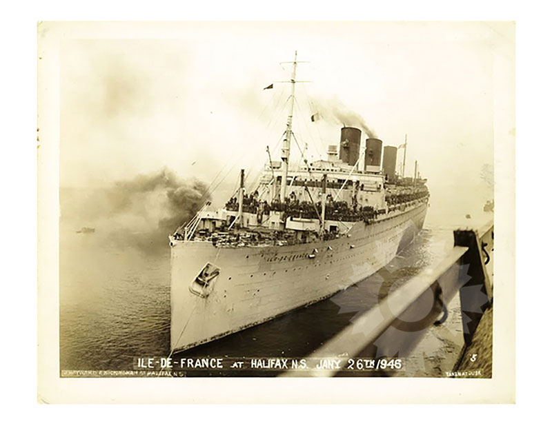 Image aux tons sépia du SS Île-de-France arrivant à Halifax, vu de la proue tribord, avec ses ponts bondés et ses cheminées fumantes.