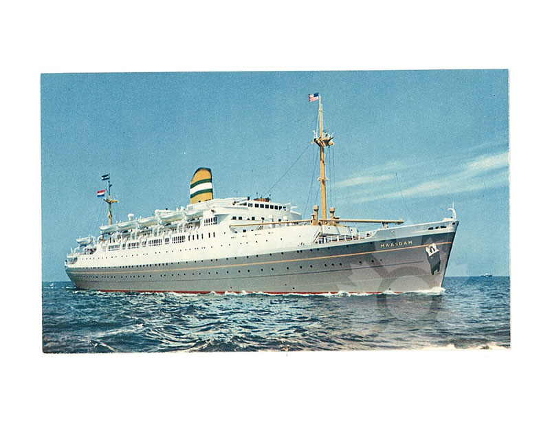 Photographie en couleur du TSS Maasdam en mer, vu de proue tribord, avec les pavillons hissés et un ciel bleu en arrière-plan.
