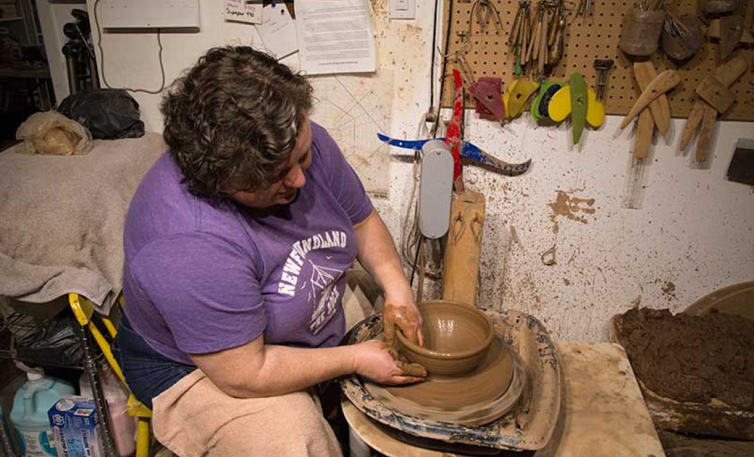 Vue latérale montrant une femme formant une poterie d’argile sur une roue.