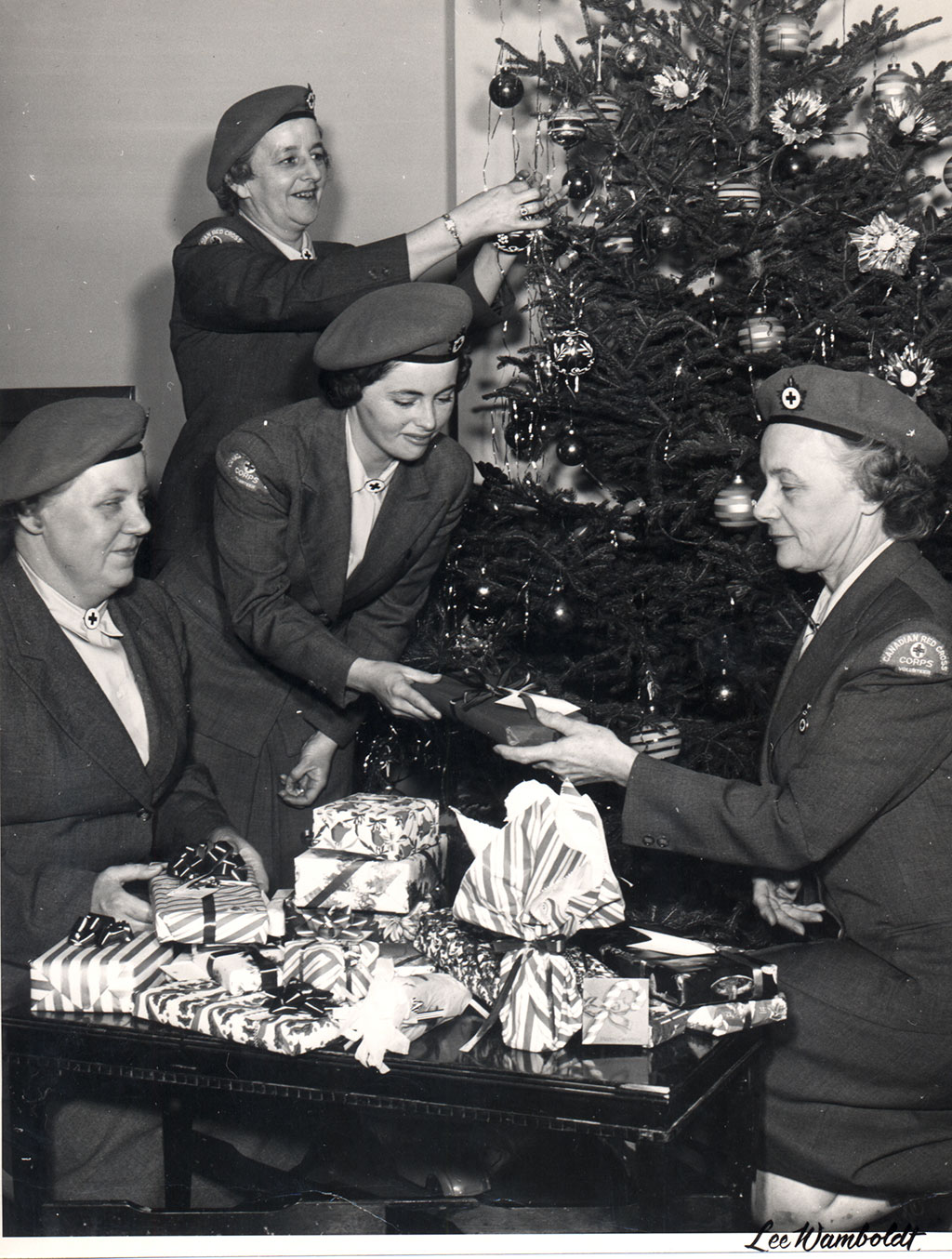 Les femmes en uniforme décorent un sapin de Noël et emballent des cadeaux.