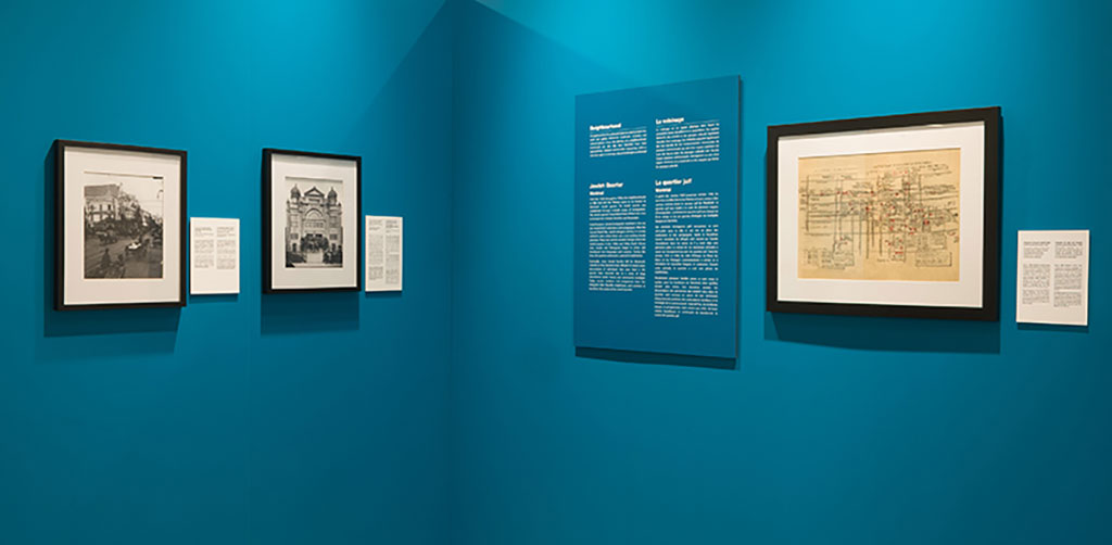 Deux sections d'un mur de couleur sarcelle. Des cadres dans lesquels se trouvent des images et du texte y sont accrochés.