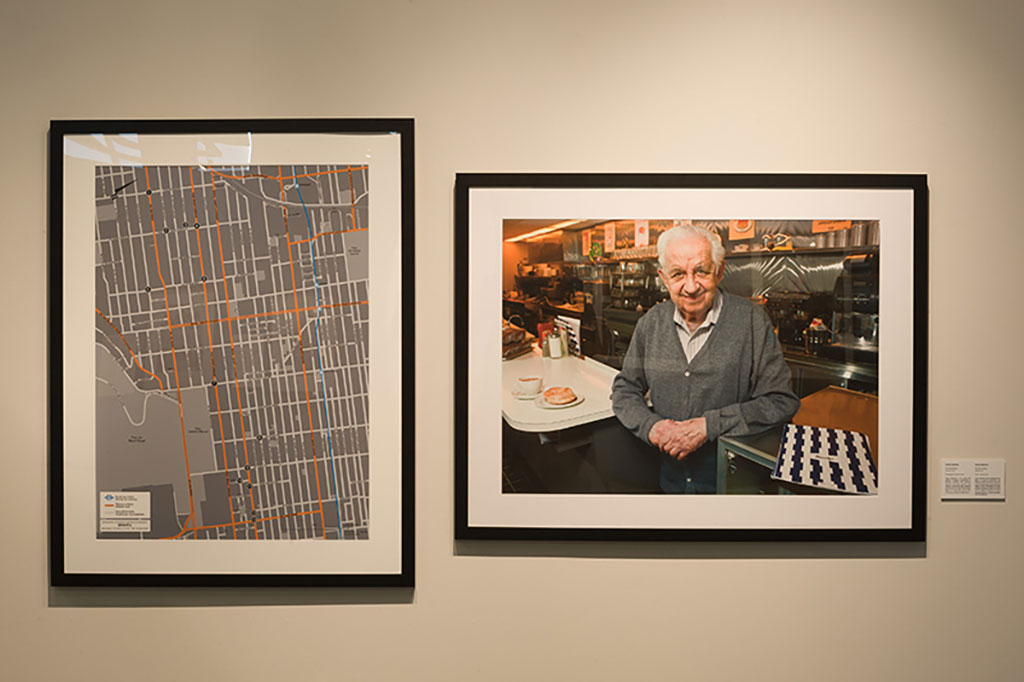 Deux images encadrées accrochées à un mur. L'une des images montre un tracé de rues et l'autre montre un homme souriant appuyé contre le comptoir d'un restaurant.