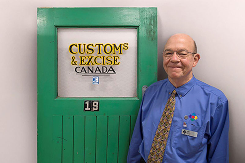 Homme souriant se tient à côté d’une porte verte.