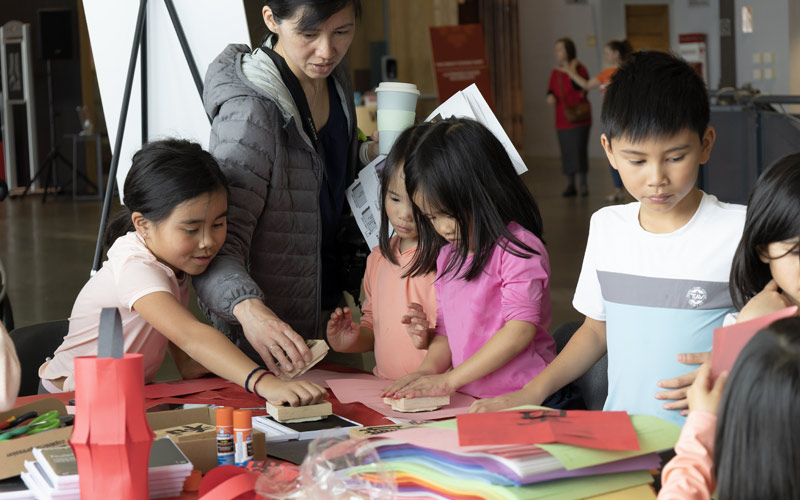 Un groupe de jeunes enfants asiatiques faisant de l’artisanat à une table dans le Musée.