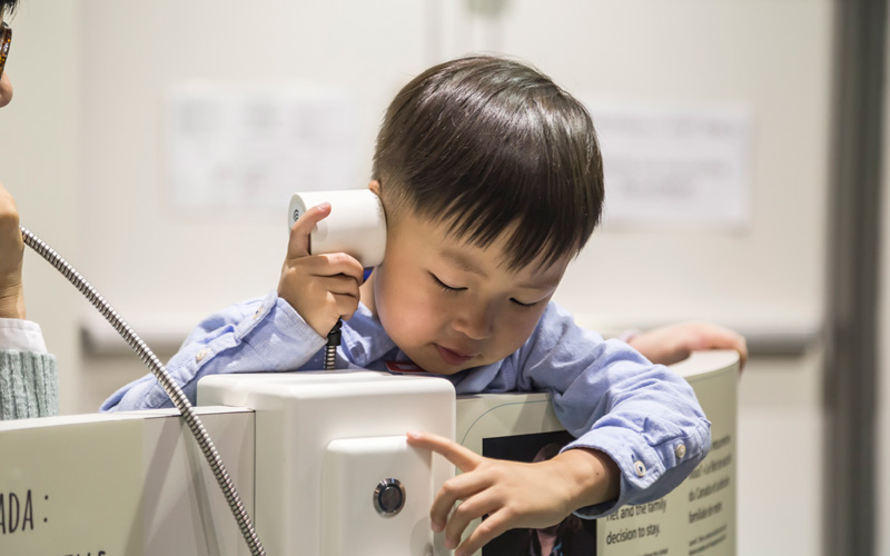 Un enfant utilise un appareil audio pour écouter une partie de l’exposition.