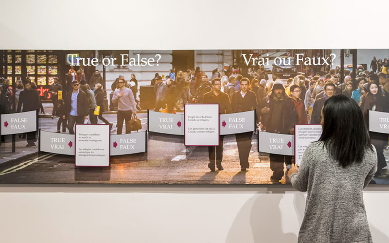 Une personne se trouve devant un panneau d’exposition qui dit « Vrai ou faux? »
