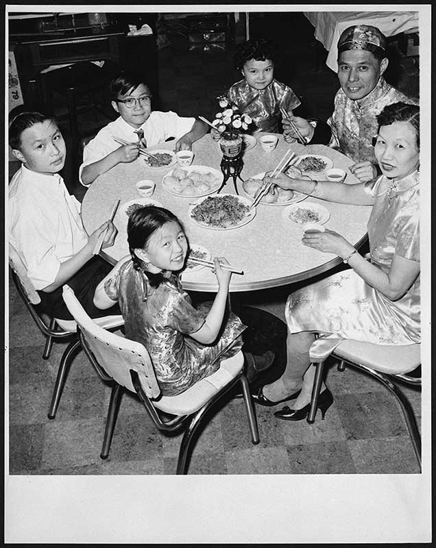 Une famille asiatique est assise autour de la table pour le repas.