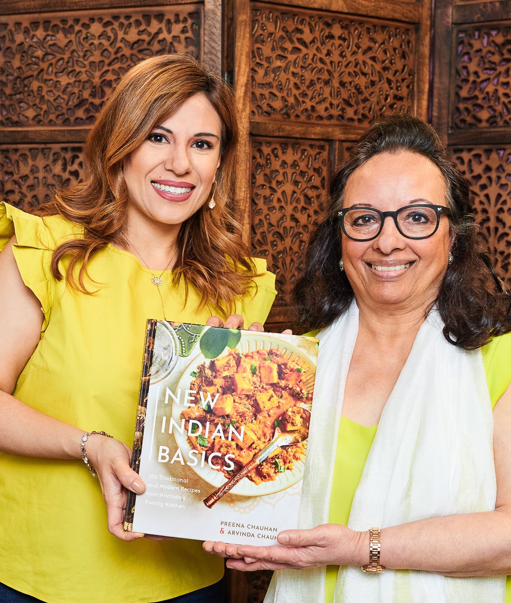 Portrait de deux femmes indiennes souriantes tenant un exemplaire de leur livre de cuisine indienne.