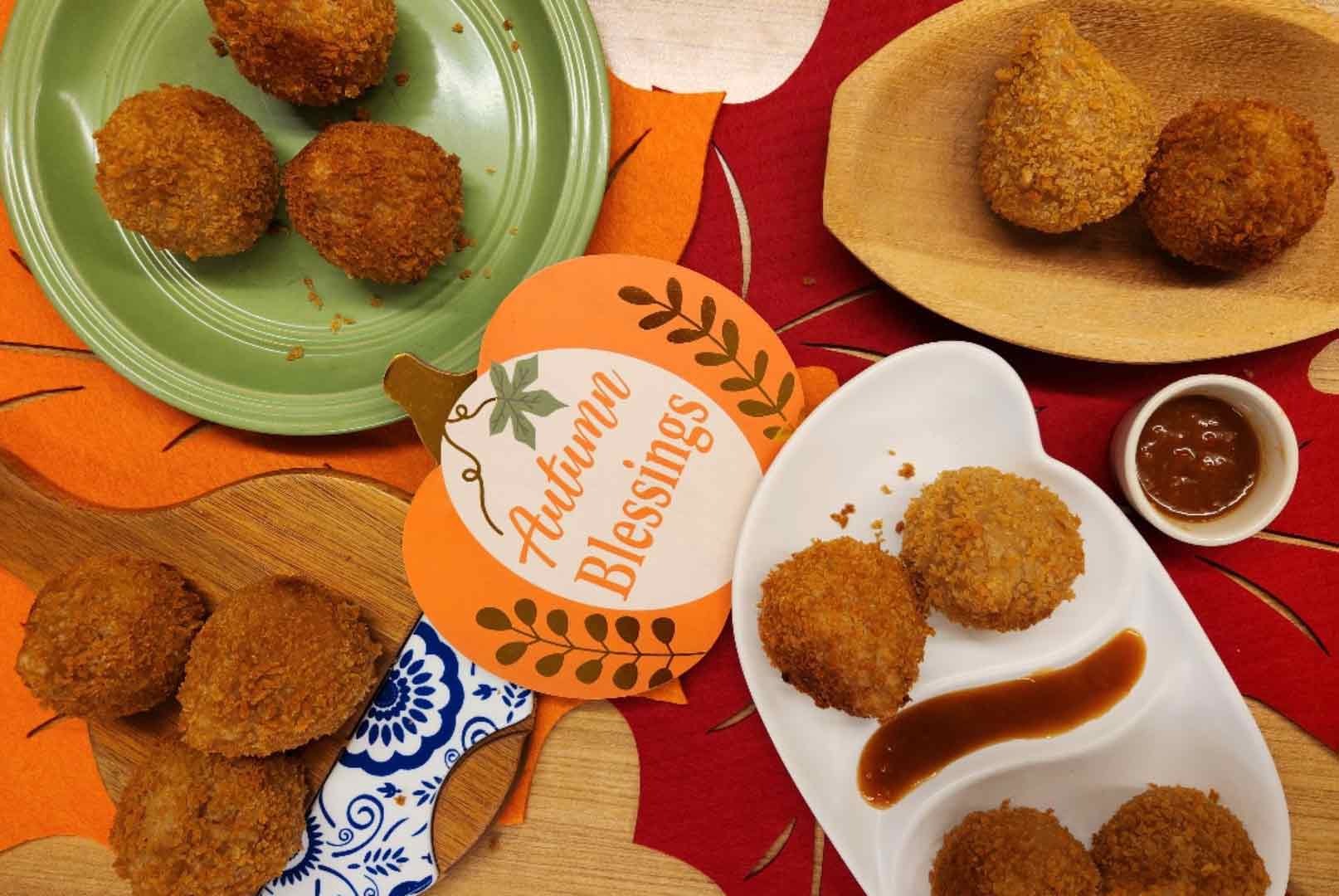 Vue du haut d’une table présentant plusieurs assiettes de coxinhas disposées sur des nattes en forme de feuilles rouges et orange.
