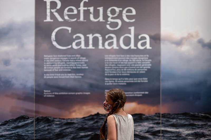 Four people look at the exhibition, including one person with professional camera equipment.