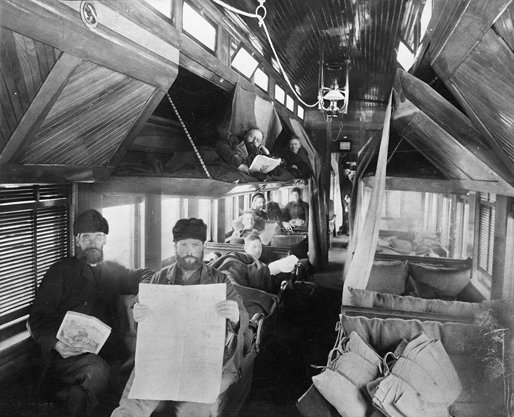 Intérieur d’une vieille voiture à vapeur, montrant des hommes dans divers états de repos.