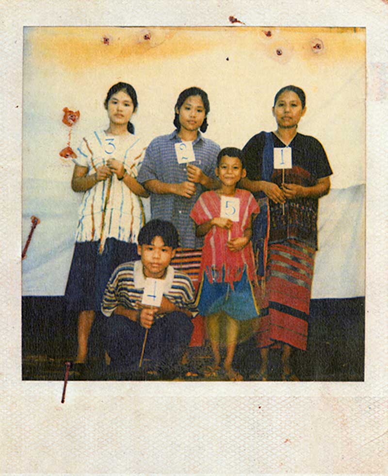 Une femme et quatre enfants tiennent des bâtons sur lesquels sont collés des papiers numérotés.