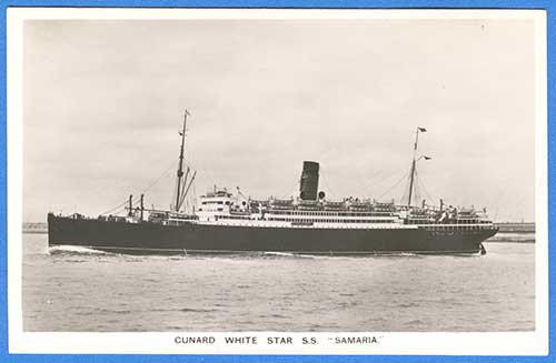 Ancienne photographie en noir et blanc d’un grand navire à vapeur. Côté bâbord, une cheminée, deux mâts. La côte est visible derrière le navire.