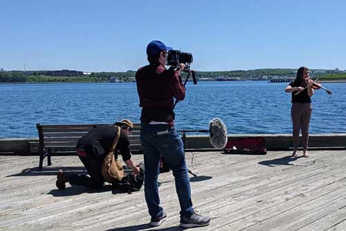 Une femme jouant du violon sur la promenade du port de Halifax est filmée et enregistrée.