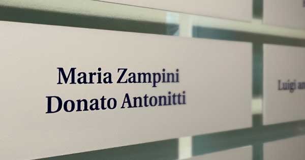 Gros plan d’une plaque se trouvant sur un mur de plaques. Elle porte les noms de Maria Zampini et de Donato Antonitti.