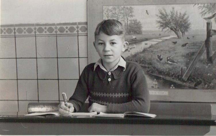 Photographie en noir et blanc d’un garçon à un pupitre.