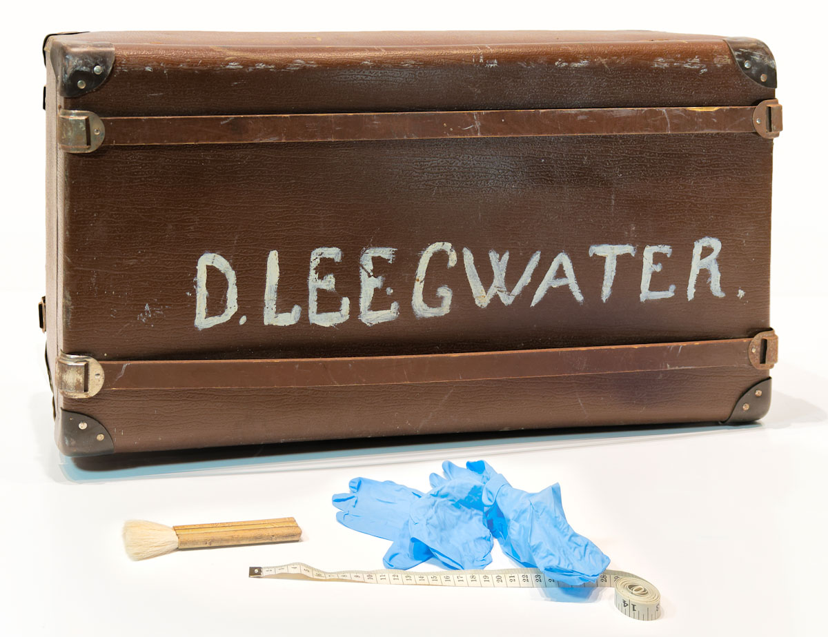 Une vieille valise avec le nom Leegwater peint en grosses lettres.