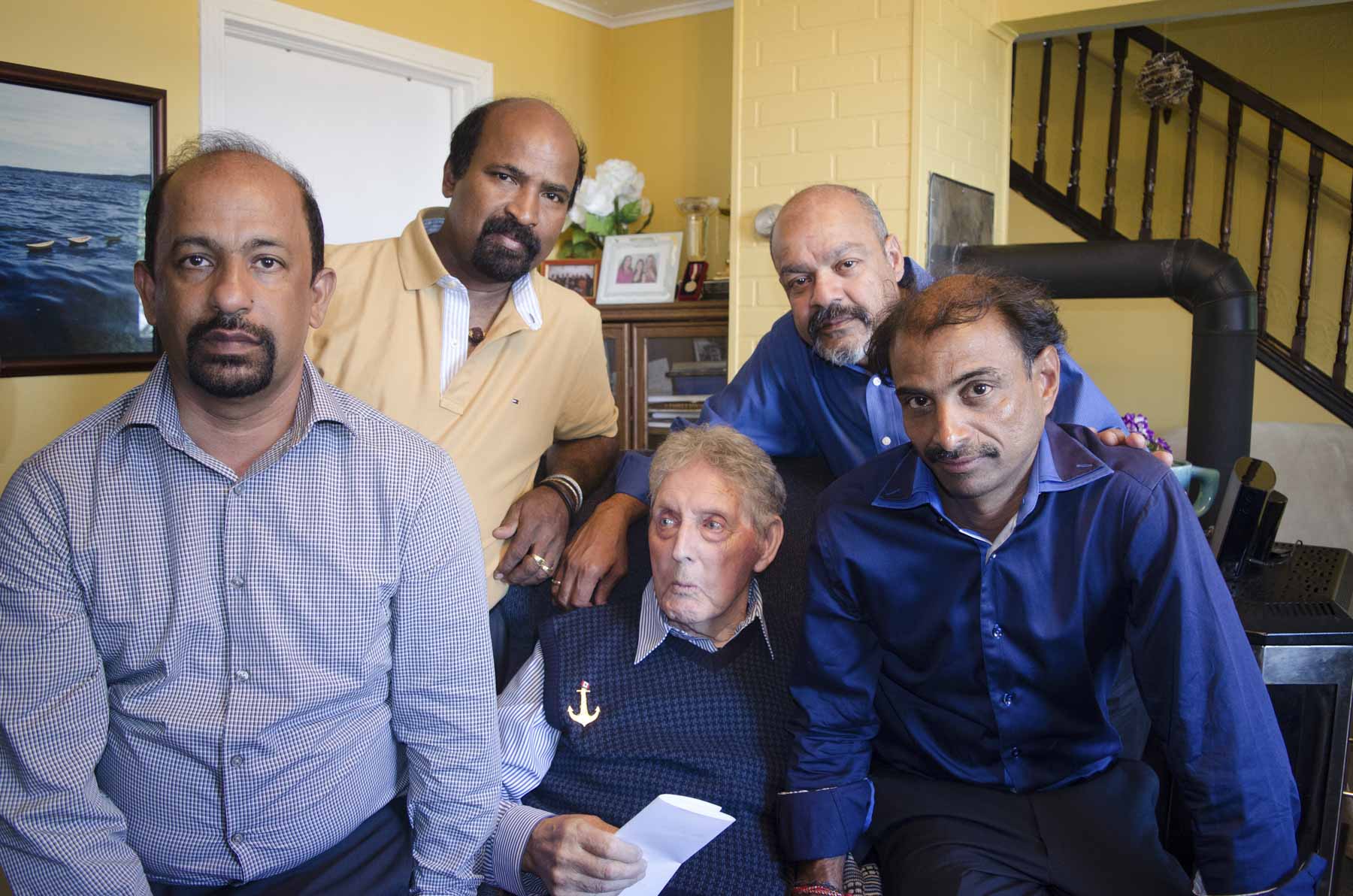 Quatre hommes tamouls d’âge moyen posent aux côtés d’un homme blanc plus âgé.