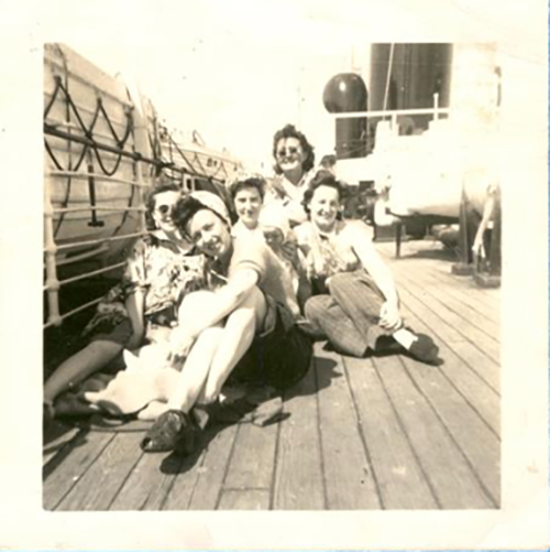 Cinq jeunes femmes sont assises sur le pont d’un navire.