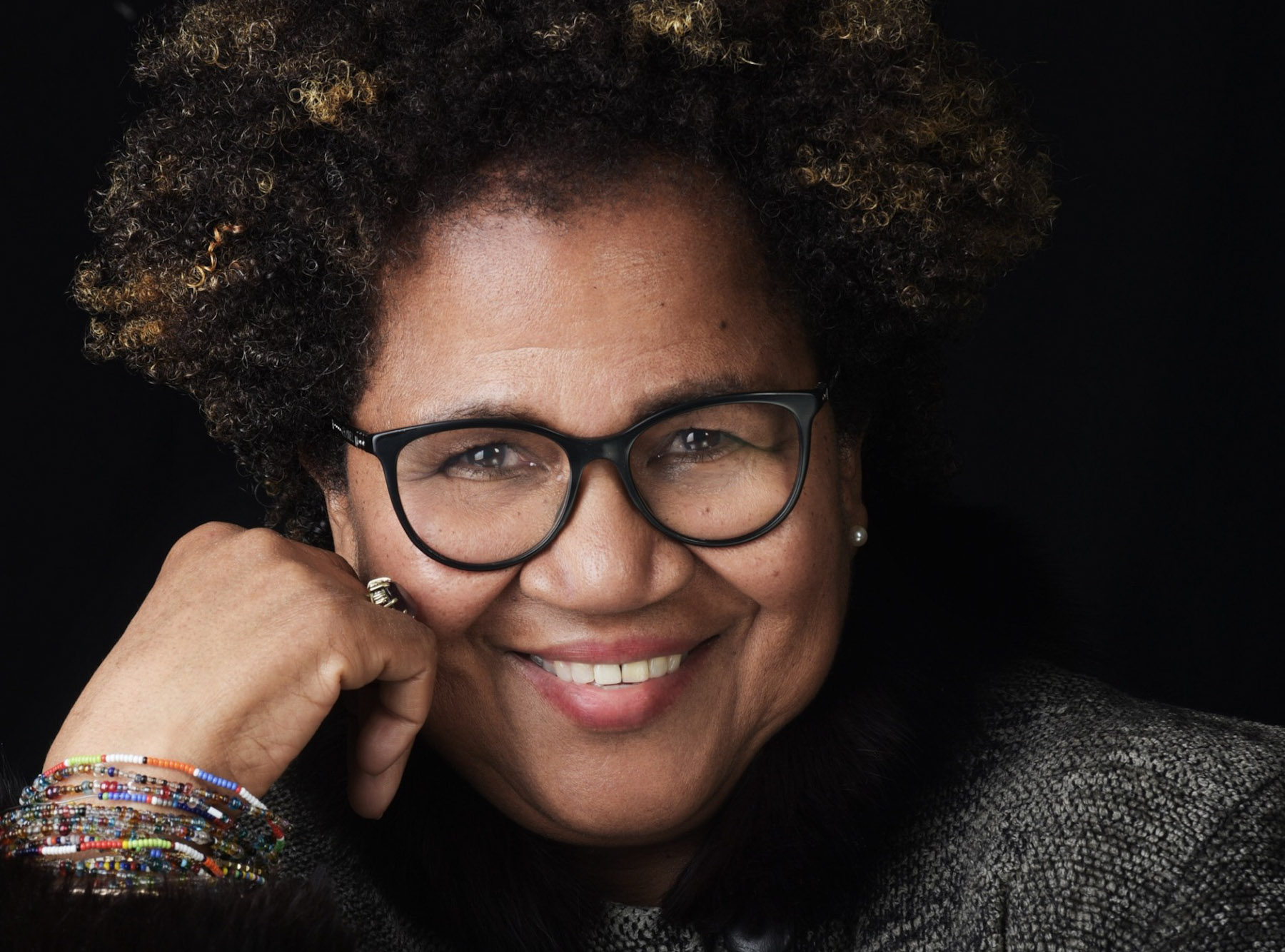 Portrait de Joy Bullen, une femme souriante à la peau foncée et portant des lunettes.