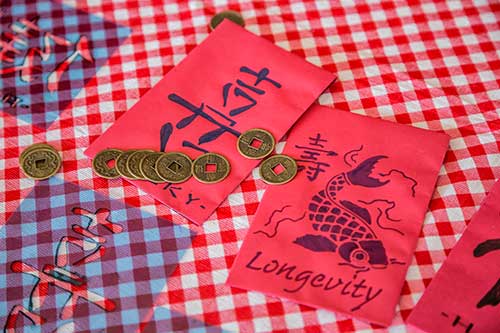Deux enveloppes rouges décorées avec des pièces à proximité.