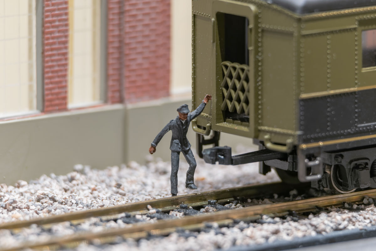 Figurine représentant un homme à la peau foncée, la main posée sur un wagon de chemin de fer.