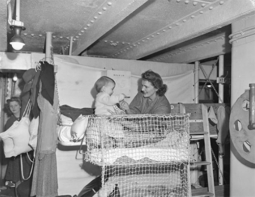 Femme joue avec bébé sur une couchette d’un vieux navire de transport.