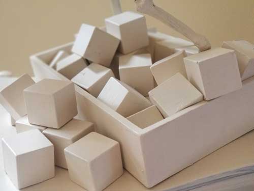 Vue rapprochée d'une boîte remplie de cubes, tous de la même nuance de beige.