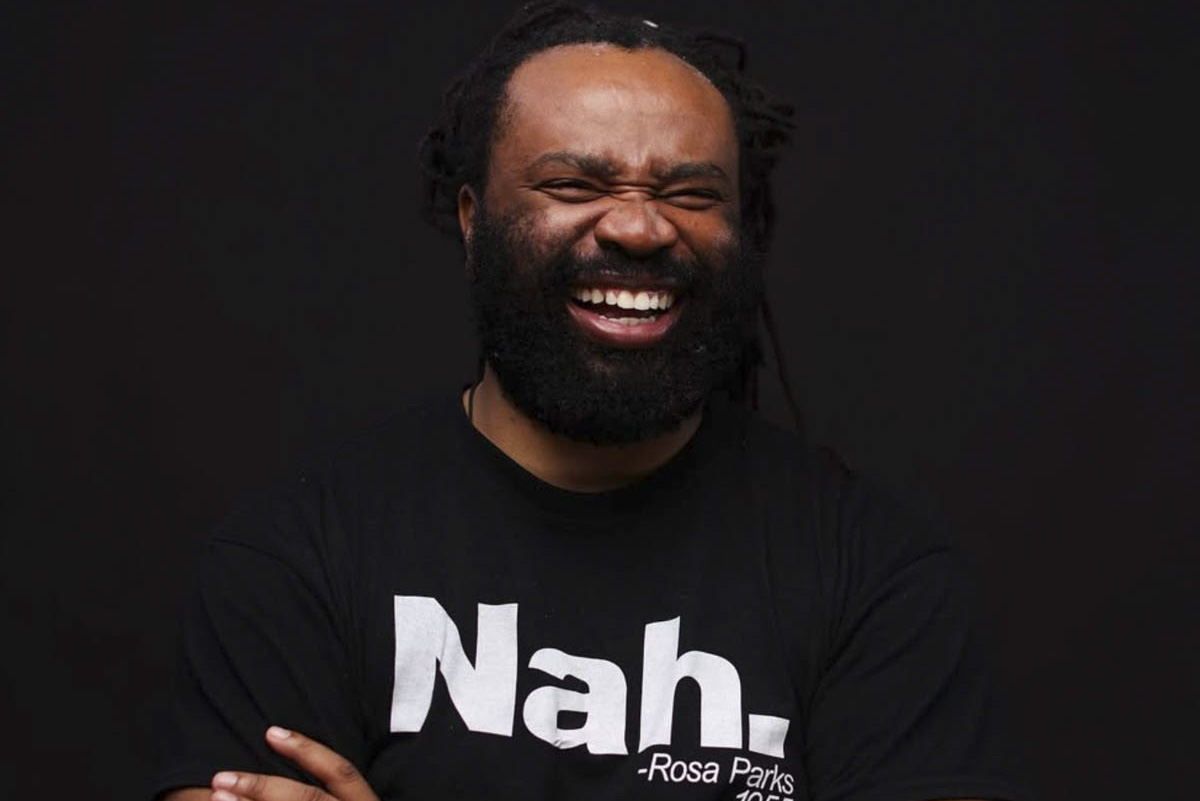 Un homme noir barbu au sourire radieux.