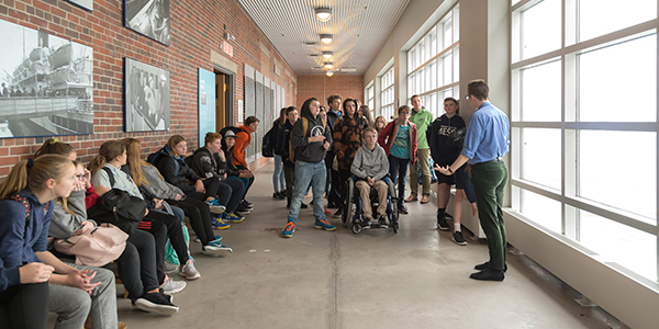 Un groupe d’adolescents regarde un membre du personnel du Musée qui fait une visite guidée.