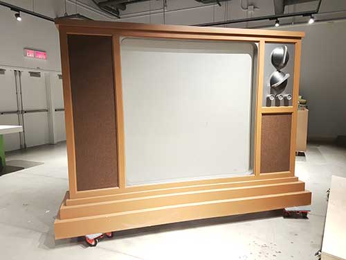 Une réplique surdimensionnée d'une télévision en bois d'époque se trouve dans un hall d'exposition.