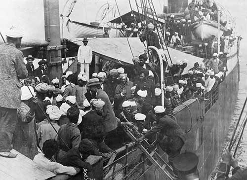 photo en noir et blanc d'un navire rempli de passagers, beaucoup portant des turbans