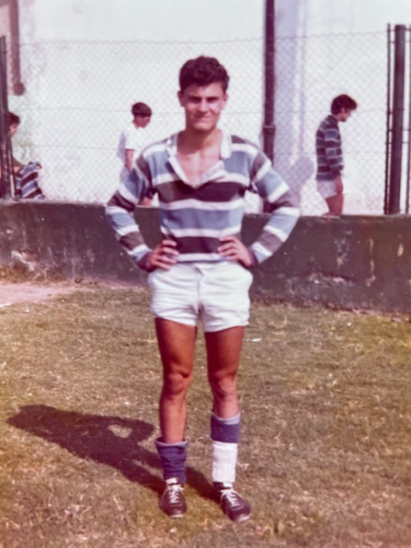 Une vieille photo d’un jeune homme portant un gilet de rugby rayé bleu et gris.