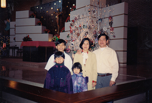 Un homme, une femme, deux garçons et une fille) devant un autel décoré d’ornements festifs.