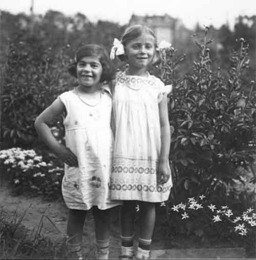 Deux jeunes filles en robes blanches se tiennent dans un jardin.