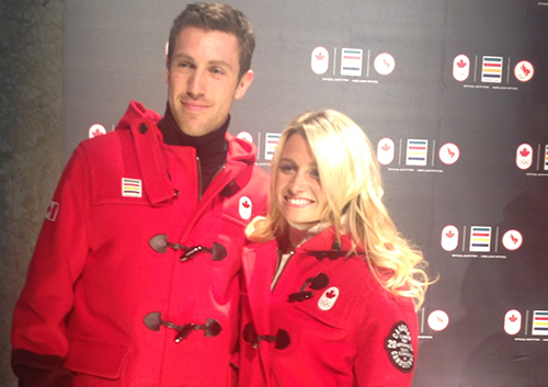 Un jeune couple portant des vêtements olympiques rouge foncé se tient debout.