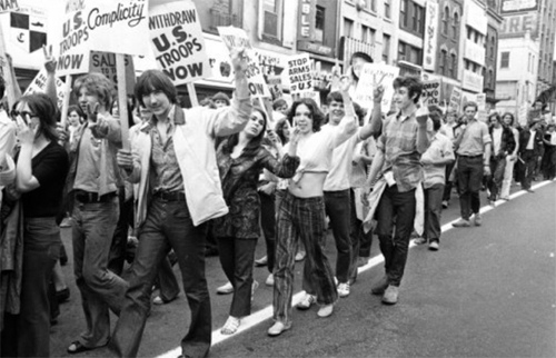Une photo archivée en noir et blanc de jeunes gens portant des pancartes, marchant en signe de protestation.