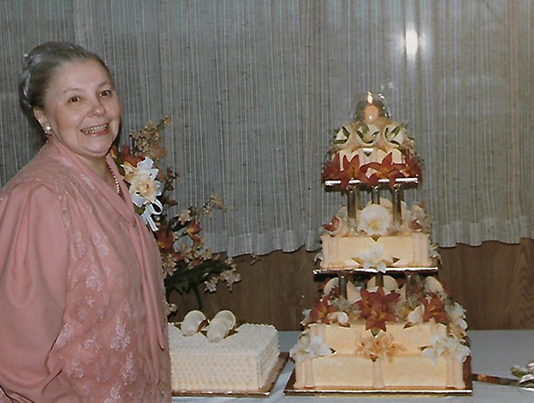 Une jeune femme se tient à côté d’un gâteau qu’elle a fait.