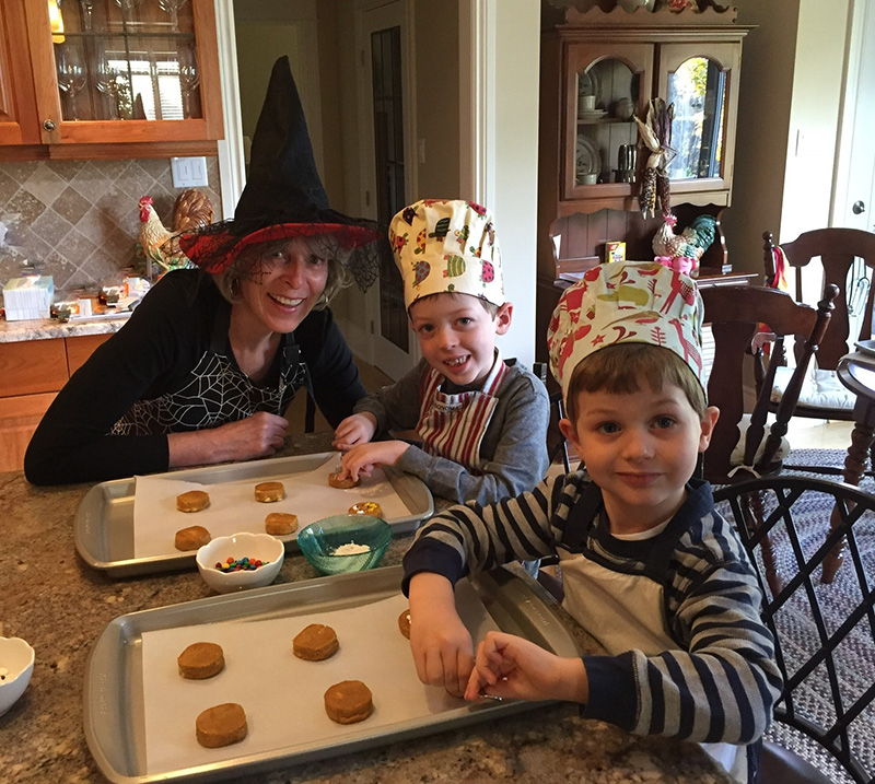 Une femme et deux jeunes garçons font des cookies pour Halloween.