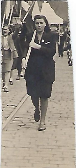Une jeune femme tient un drapeau et marche sur un chemin.