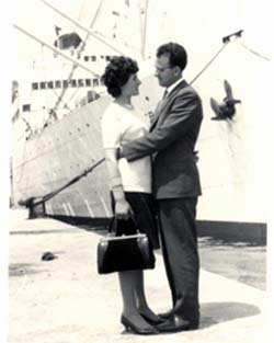 Homme et femme s’étreignant sur le quai avec le bateau en arrière-plan.