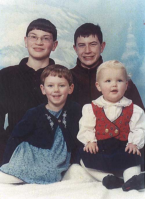 Deux jeunes hommes debout derrière deux enfants mignons pour une photo.